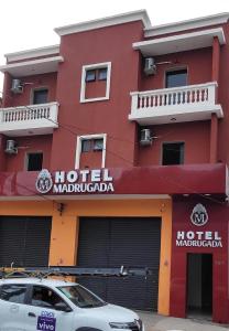 un hotel rosso con una macchina parcheggiata di fronte di Hotel Madrugada a San Paolo