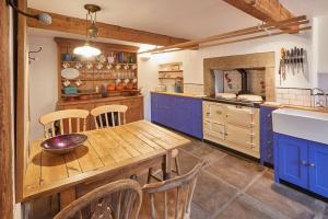 une cuisine avec une table en bois et des armoires bleues dans l'établissement Stunning 3 bed Yorkshire Dales cottage, à Appletreewick