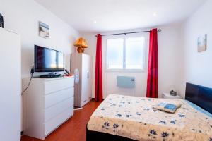 a bedroom with a bed and a television and red curtains at Le Tau in Saintes-Maries-de-la-Mer