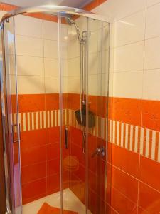 een douche in de badkamer met oranje en witte tegels bij Casa vacanze MELFA in Atina