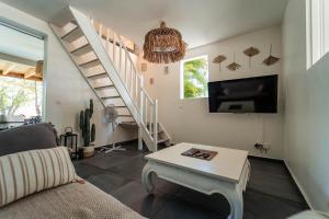 a living room with a couch and a tv and stairs at La Petite Caravelle Guadeloupe in Sainte-Anne