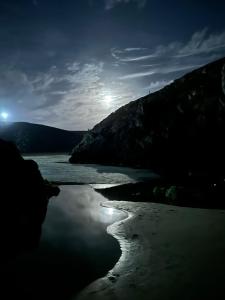 una vista del río por la noche con la luna en Mirleft Trip, en Mirleft