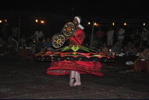 um homem num vestido colorido com uma ventoinha em safari desert em Bawati