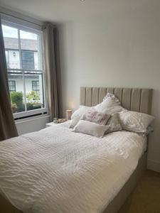 a bedroom with a white bed with pillows and a window at Spacious 1-bedroom apartment in Belsize Village in London