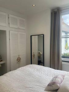 a white bedroom with a bed and a mirror at Spacious 1-bedroom apartment in Belsize Village in London