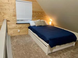 NEW Modern Cabin! 5mi to Mt Rainier National Park! Hot Tub & Wifi في أشفورد: غرفة نوم بسرير في غرفة بجدران خشبية