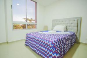 una camera da letto con un letto con una coperta colorata e due finestre di Ayenda Salome Apartments a Cartagena de Indias