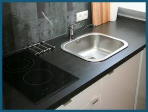 a kitchen counter with a sink and a stove at Moderne Wohnung mit Wellnessdusche und Strandkorb in Braunschweig