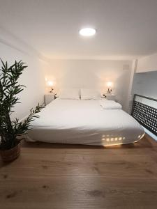 - une chambre avec un lit doté de draps blancs et d'une plante dans l'établissement MiniLoft Baiona -, à Baiona