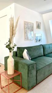 - un canapé vert dans le salon avec un vase sur une table dans l'établissement Chez Clément et Mathilde -Duplex climatisé Hyper centre , tout équipé, à Saint-Amand-les-Eaux