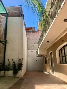 un callejón entre dos edificios con una palmera en La Casa del Mercado, en San Miguel de Allende