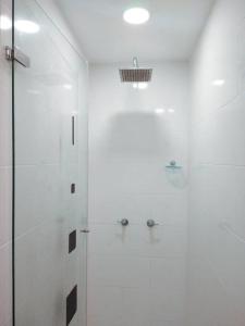 a white bathroom with a shower and a glass door at Apartamento Cómodo y Moderno, La Mejor Ubicación, Cerca al Metro Tranvía in Medellín