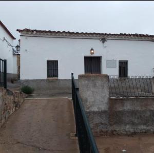 un edificio blanco con una valla delante en La casita en la Alcornocosa -Sevilla, en Sevilla