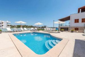 a swimming pool with umbrellas on a building at Villa Sa Caleta Private sea & spa in Portocolom