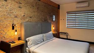 1 dormitorio con cama y pared de ladrillo en Casa Corazon, en Guadalajara