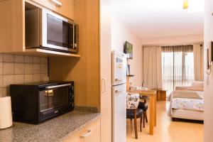 eine Küche mit einer Mikrowelle und ein Wohnzimmer in der Unterkunft Alojamientos Bariloche in San Carlos de Bariloche