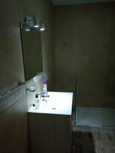 uma casa de banho com um lavatório branco e um espelho. em Lalúan departamento temporario em Ushuaia
