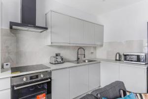 a kitchen with white cabinets and a sink at Elegant Croydon Apartment in London