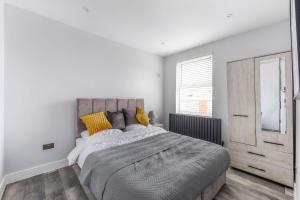 een witte slaapkamer met een groot bed met gele kussens bij Elegant Croydon Apartment in Londen