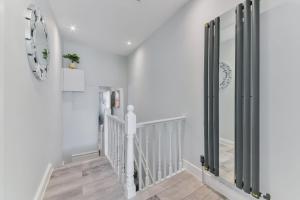 een hal met witte muren en een trap met een spiegel bij Elegant Croydon Apartment in Londen