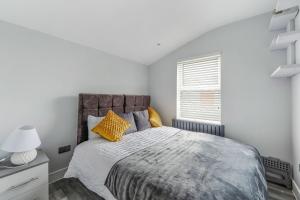 a white bedroom with a large bed with yellow pillows at Elegant Croydon Apartment in London