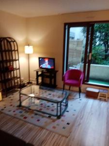 a living room with a glass coffee table and a tv at Studio Cosy avec terrasse face au parc des expositions in Vanves