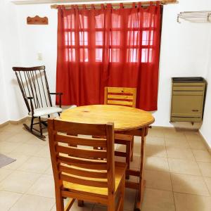 una mesa y sillas en una cocina con cortina roja en Mi depa en Esquel en Esquel