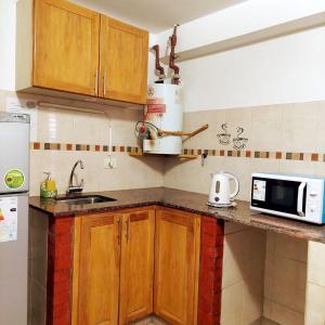 une cuisine avec des placards en bois et un four micro-ondes sur un comptoir dans l'établissement Mi depa en Esquel, à Esquel