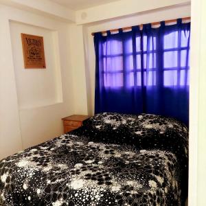 a bedroom with a black and white bed with a window at Mi depa en Esquel in Esquel