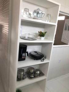 a white shelf with pots and pans in a kitchen at CASA PARA TEMPORADA CAMPINA GRANDE! in Campina Grande