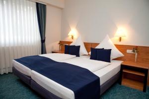 Una habitación de hotel con una cama grande con almohadas azules. en Landhotel Imhof, en Neuhof 12 fotos más