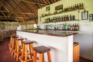 a bar with wooden stools and bottles on the wall at Bwana Tembo Safari Camp in Paraa