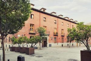 ein großes rotes Backsteingebäude mit Bäumen davor in der Unterkunft Palacio Conde Miranda in Madrid