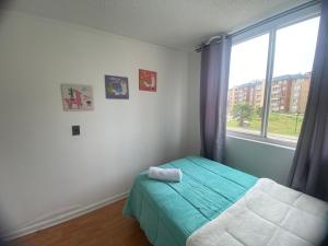 a bedroom with a bed and a large window at Apartamento altos del boldo in Curicó