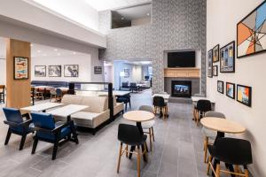 a waiting room with tables and chairs and a fireplace at Hyatt House Colorado Springs Airport in Colorado Springs