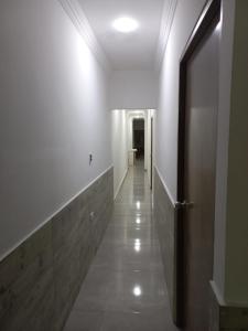 a hallway with white walls and a wooden door at Hostal Emanuel in Aracataca