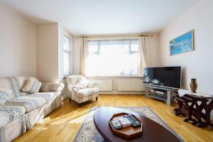 uma sala de estar com um sofá e uma televisão em Wembley Arch View, 4-Bed House, Drive for 2 cars em Londres