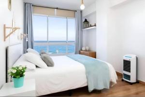 - une chambre avec un lit blanc et une grande fenêtre dans l'établissement Apartamento en Candelaria, à Candelaria