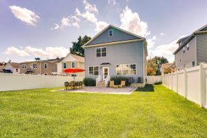 a house with a white fence in a yard at Sleek Long Branch Vacation Rental with Yard and Patio! in Long Branch