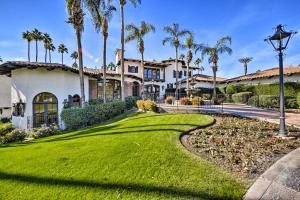 a house with palm trees and a green lawn at Golf Course, Pool Access Palm Desert Condo! in Palm Desert