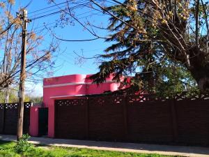 a pink building behind a fence at Family Place II in Luján