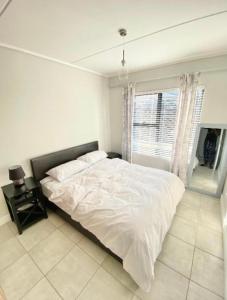 a white bedroom with a bed and a window at Offline in Boksburg