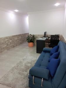 ein Wohnzimmer mit einem blauen Sofa und einem Schreibtisch in der Unterkunft Hostal Emanuel in Aracataca