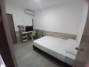 Schlafzimmer mit einem Bett und einem Schreibtisch mit einem Computer in der Unterkunft Hostal Emanuel in Aracataca