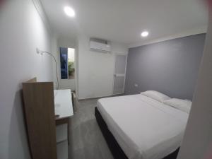 1 Schlafzimmer mit einem weißen Bett und einem Badezimmer in der Unterkunft Hostal Emanuel in Aracataca