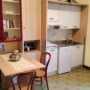 モンテグラナーロにあるB&B ROSSELLAの白いキャビネット、テーブルと椅子付きのキッチンが備わります。