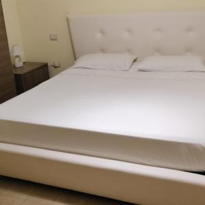 Cama en habitación con sábanas blancas en B&B ROSSELLA en Montegranaro