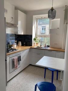 kuchnia z białymi szafkami, stołem i zlewem w obiekcie Pajczur home - 40m2 w Warszawie