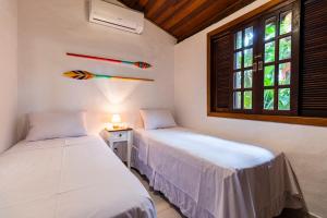 2 camas en una habitación con ventana en Vila Damai Maresias, en Maresias