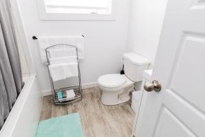 a white bathroom with a toilet and a towel rack at The Apartment in Deer Lake